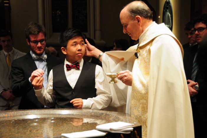 Fr. Peter Rocca, CSC, the rector of the Basilica, blesses Lin as he prepares to baptize him. 